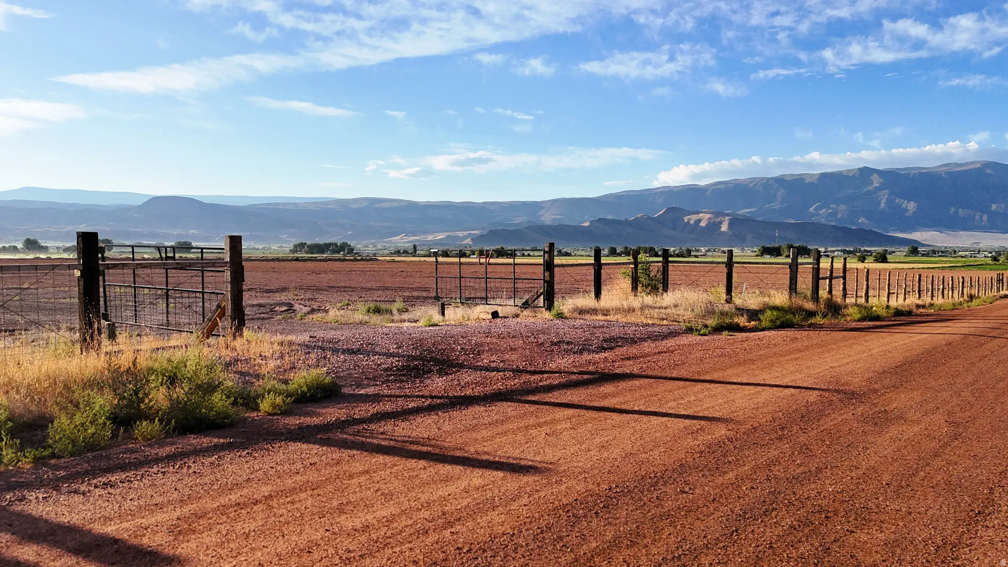 Expansive open field with fencing and mountain backdrop