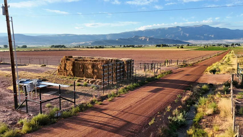 Expansive rural property featuring well-appointed livestock handling facilities with sturdy metal corrals and gates, red dirt ranch road frontage, and commanding vistas of mountain ranges and valley plains