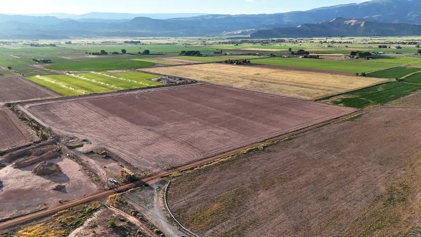 Expansive land parcel with varied terrain, surrounded by cultivated fields and distant mountain ranges