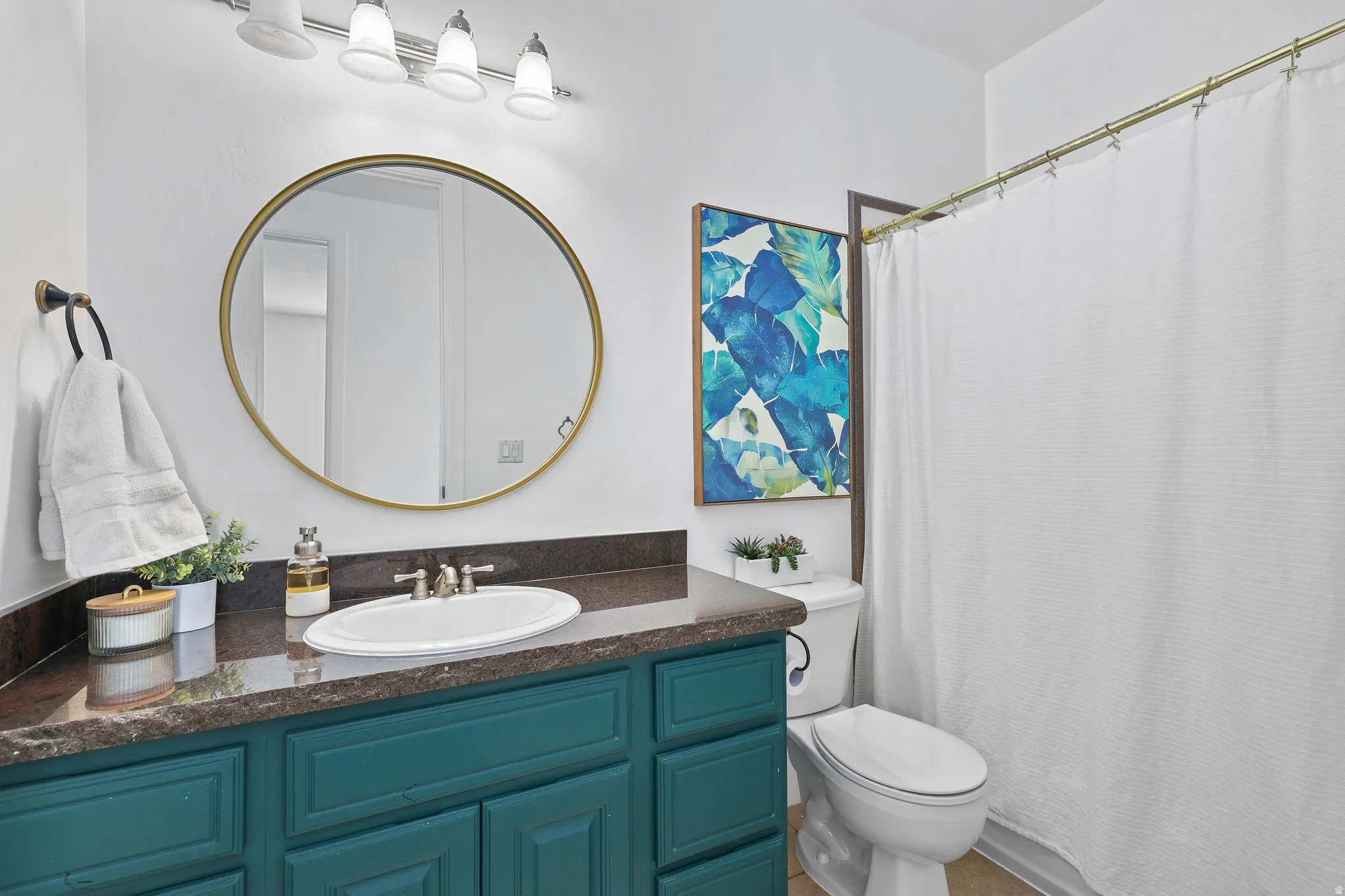 Vanity with integrated sink, dark countertop, and teal cabinetry