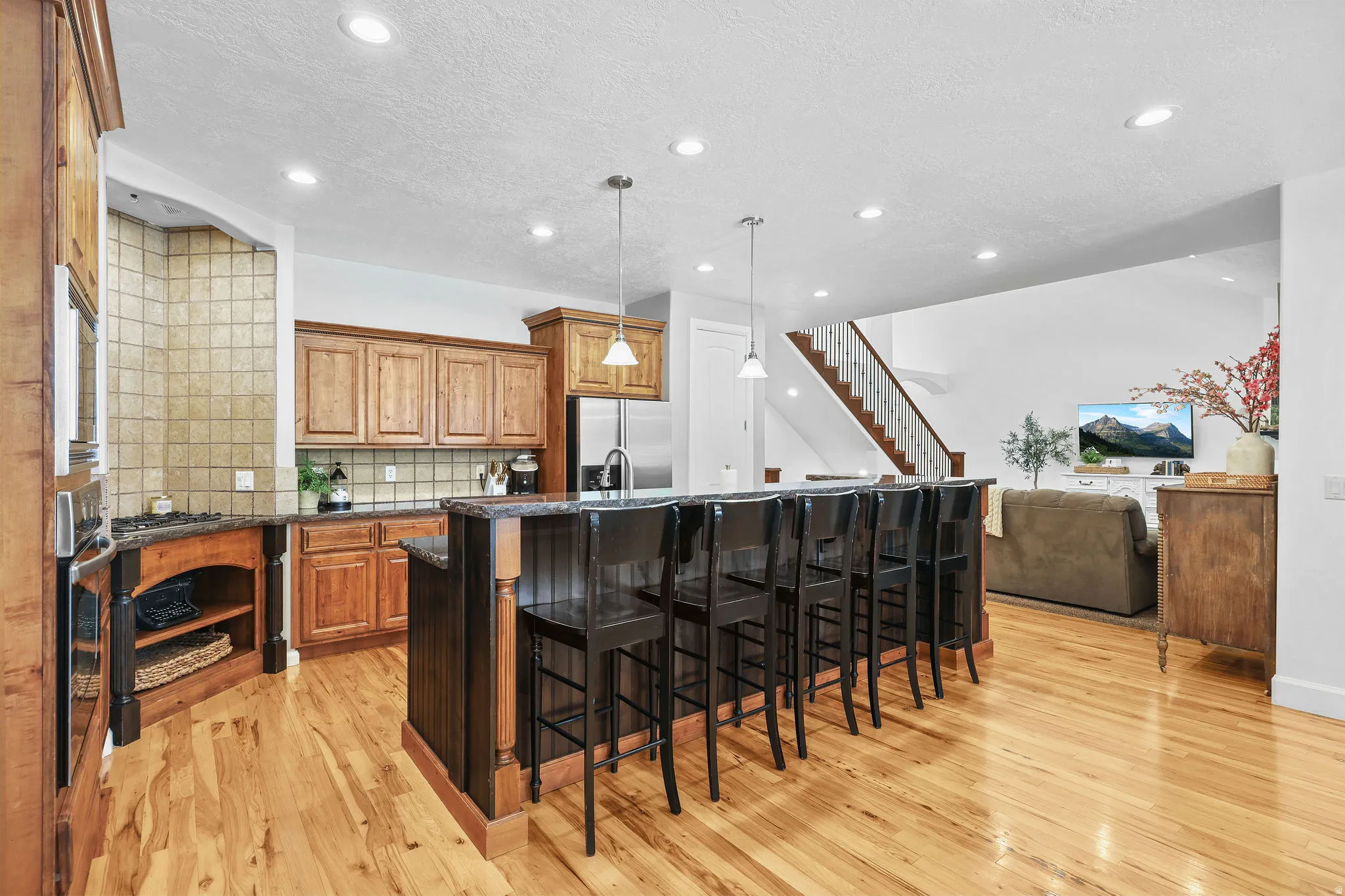 Open-concept kitchen featuring wood cabinetry, an extended kitchen island with bar seating, and stainless steel appliances