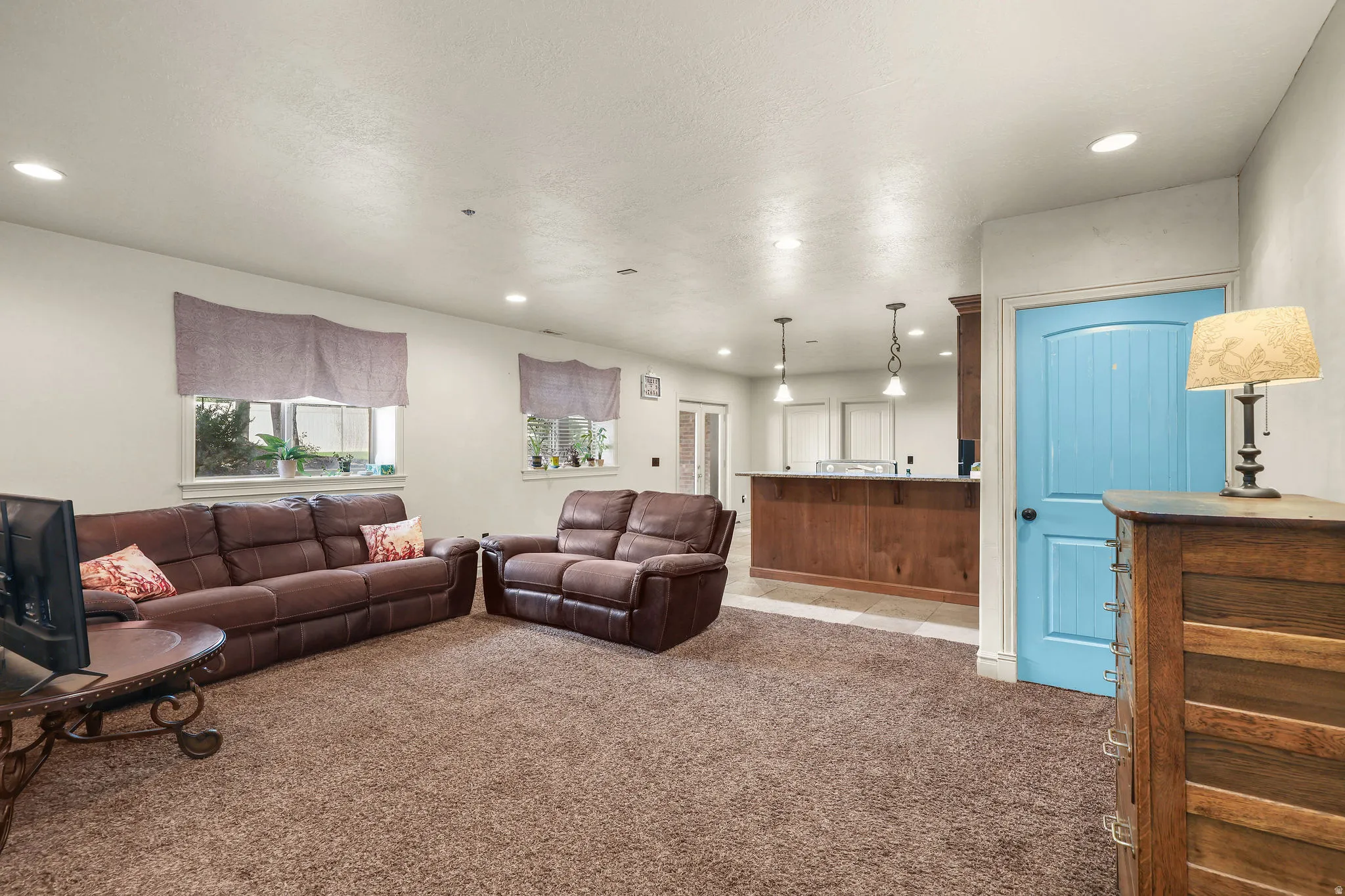 Recessed lighting, wood-finish bar, two windows, carpeted flooring, and a paneled door