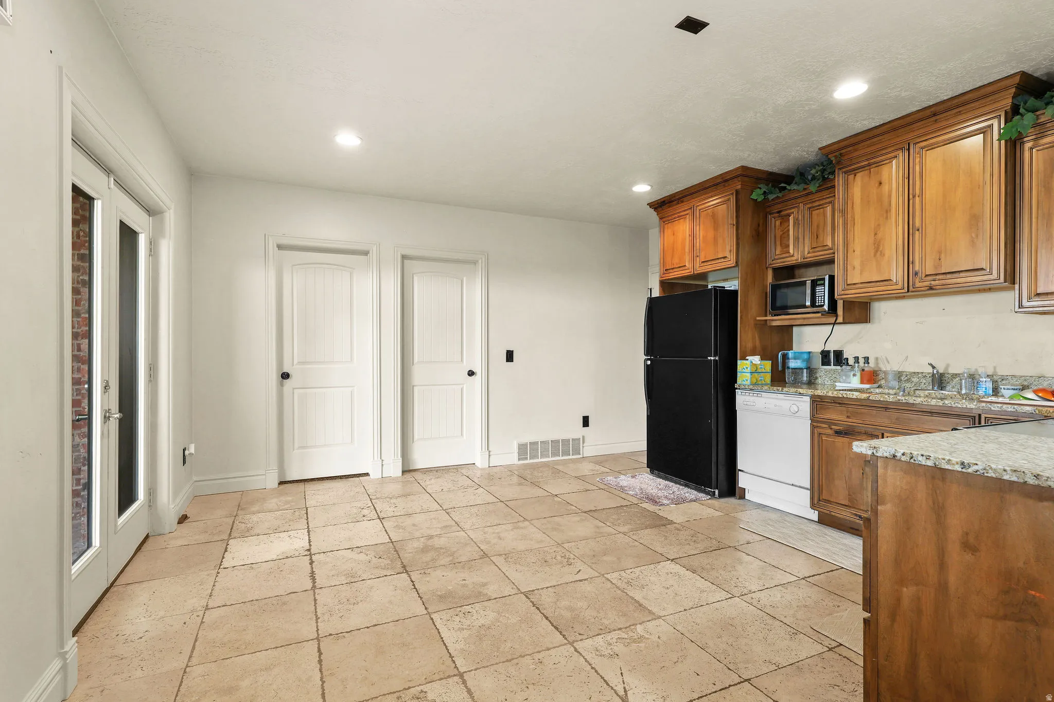Tile flooring, wood cabinetry, built-in microwave, French doors, recessed lighting