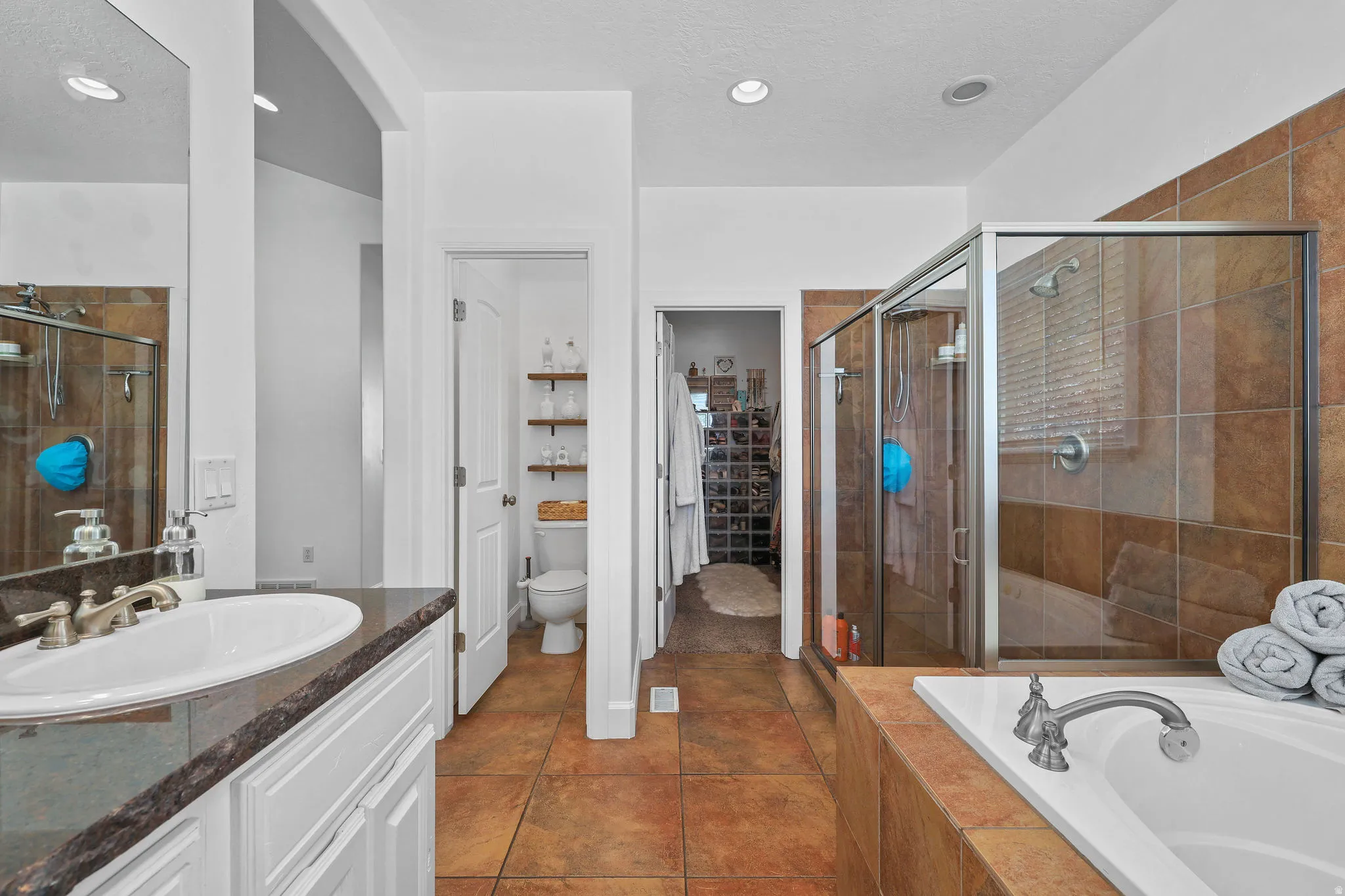 White vanity with a dark countertop, an undermount sink, and brushed nickel fixtures