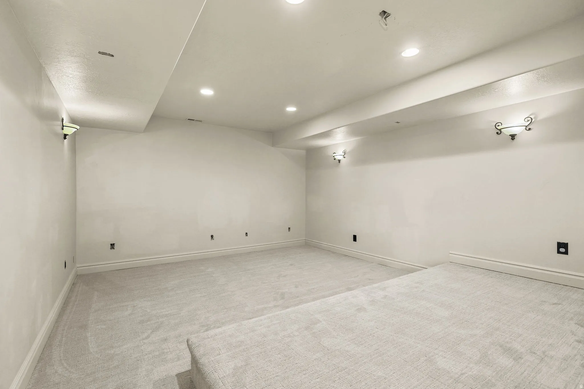 Recessed lighting, wall sconces, plush carpet flooring, and a raised platform