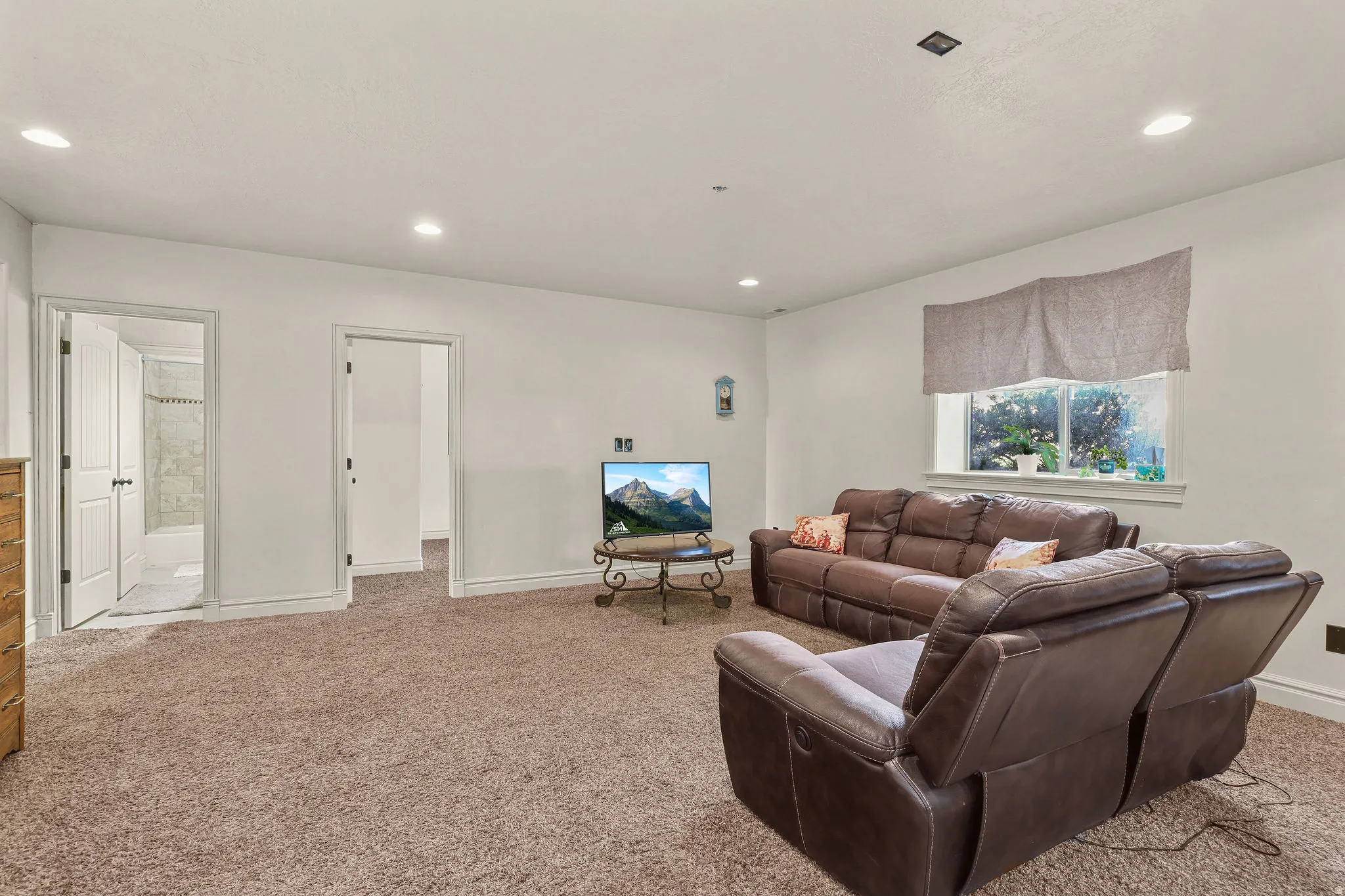 Recessed lighting, light-colored walls, window with natural light, and two interior doorways