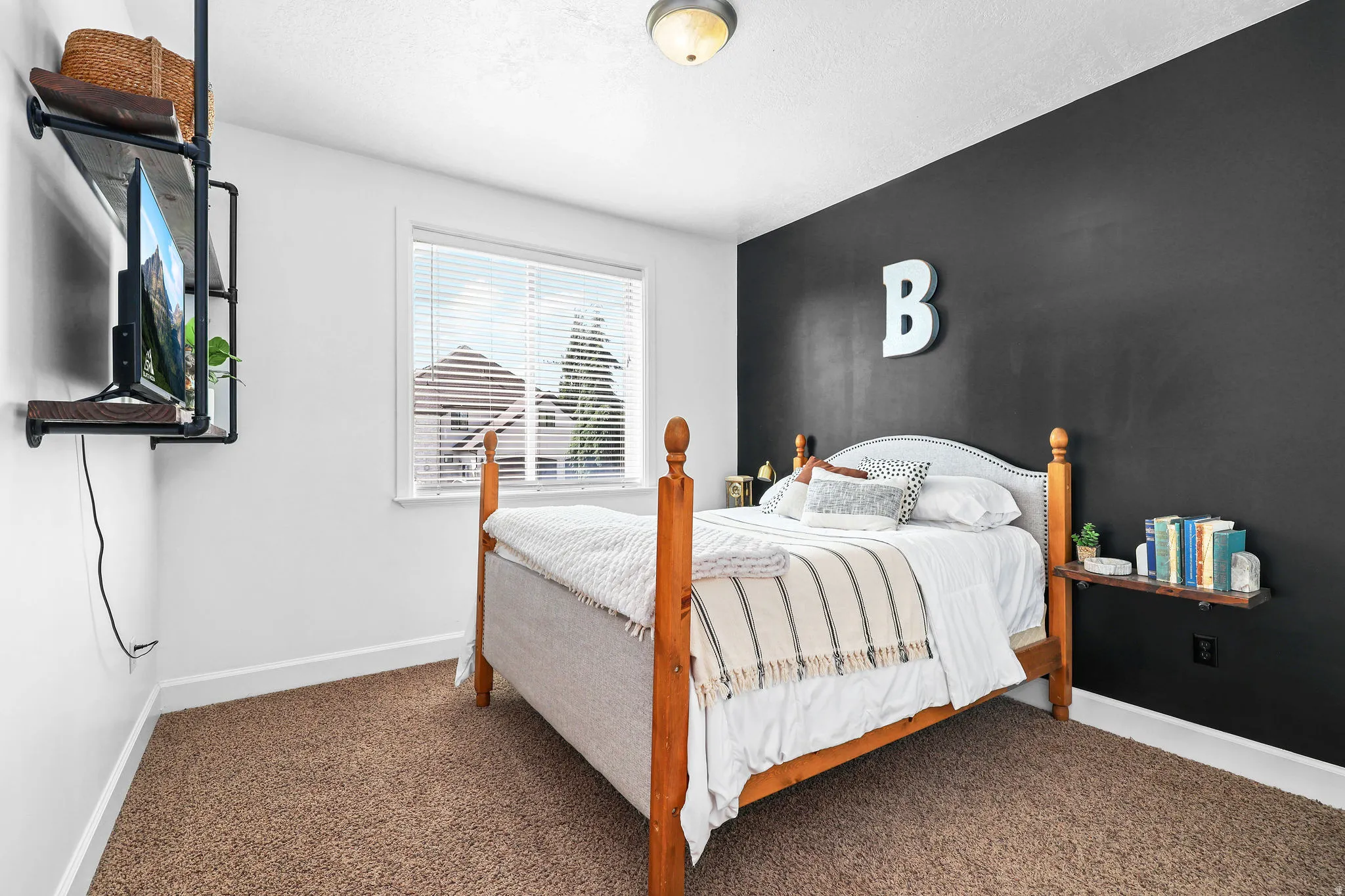 White walls with a contrasting accent wall, ceiling-mounted light fixture, window with horizontal blinds, and carpeting
