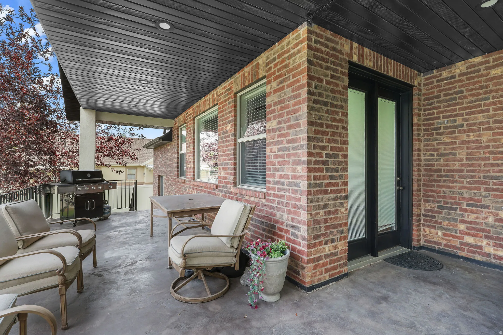 Covered patio with brick exterior, concrete flooring, and recessed lighting