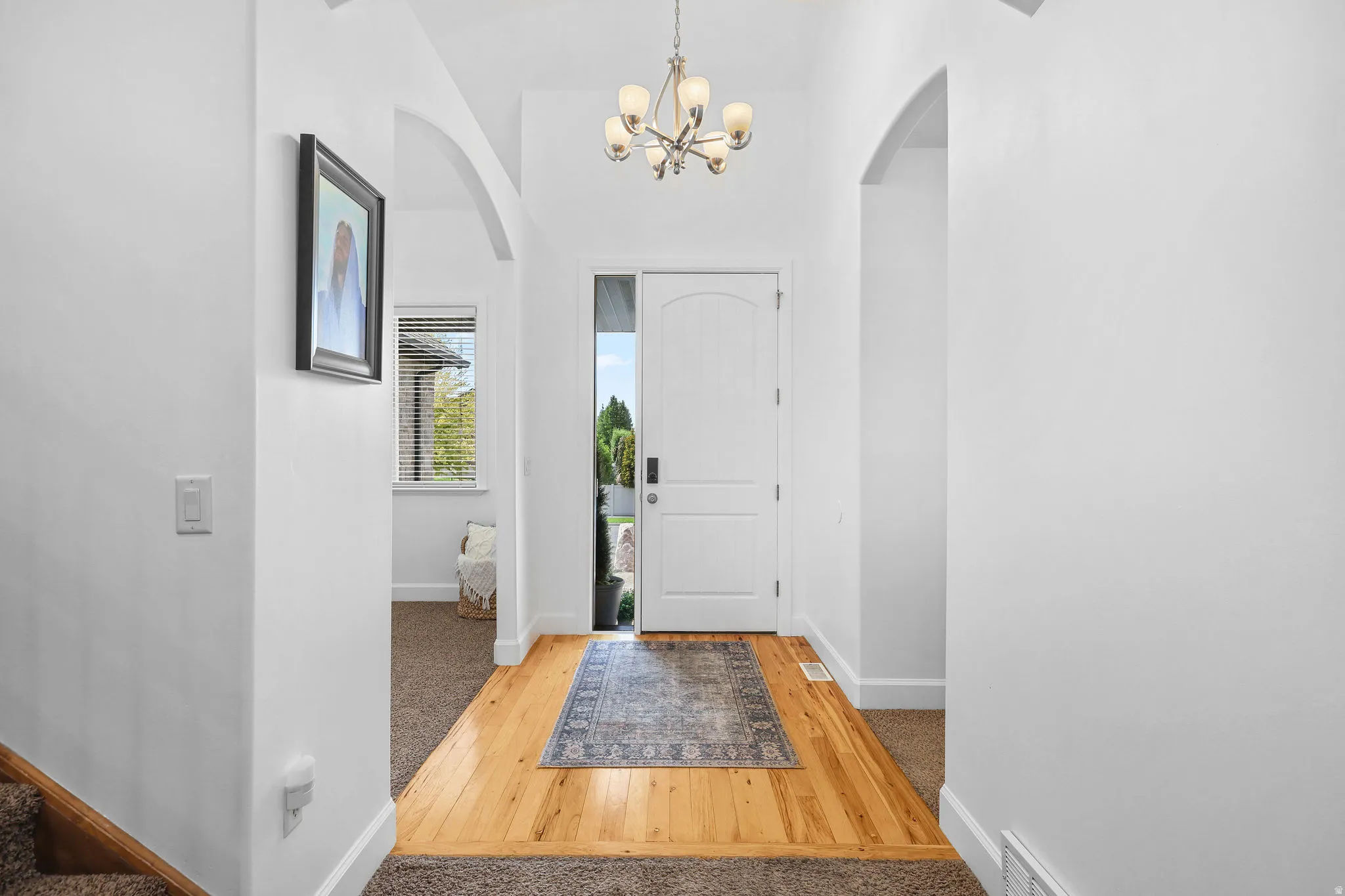 Entryway featuring wood-finish flooring, a contemporary chandelier, and a white paneled door with a sidelight