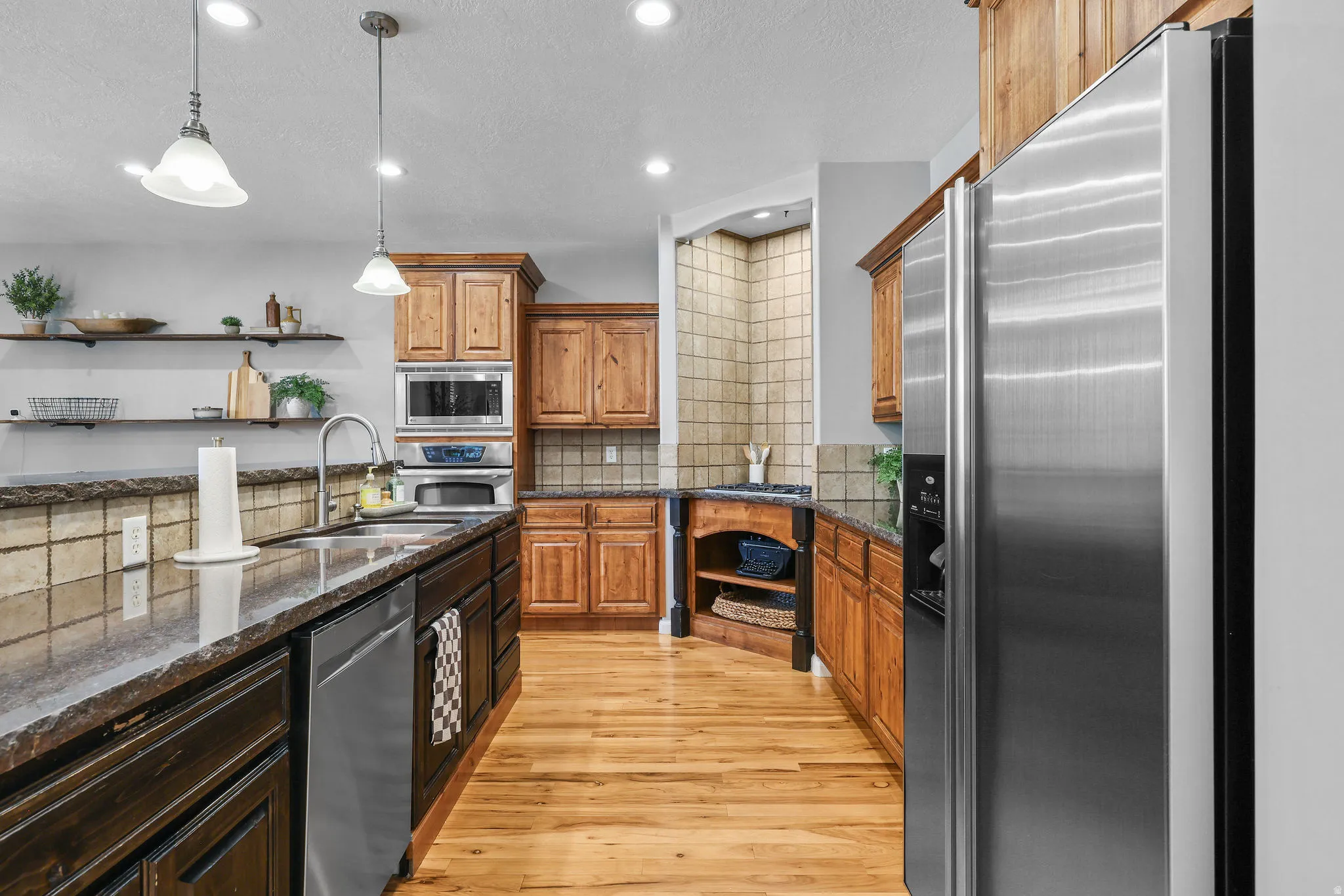 Spacious kitchen featuring stainless steel appliances, wood-finish flooring, recessed lighting, and granite countertops
