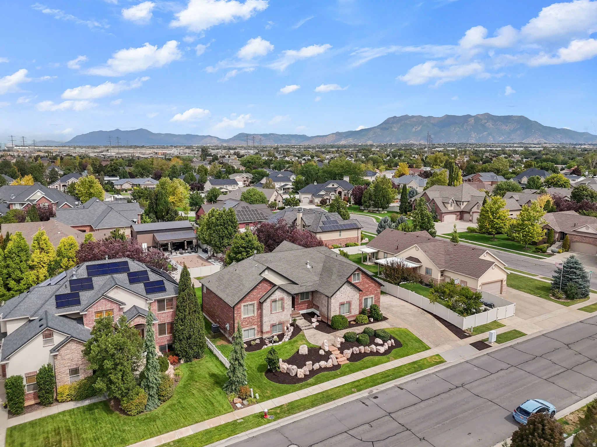 Brick exterior with stone accents, mature landscaping, paved driveway, and established neighborhood setting