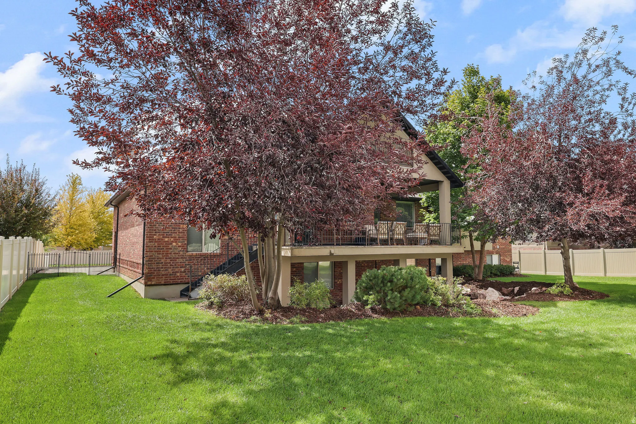 Manicured lawn with mature trees and a private deck