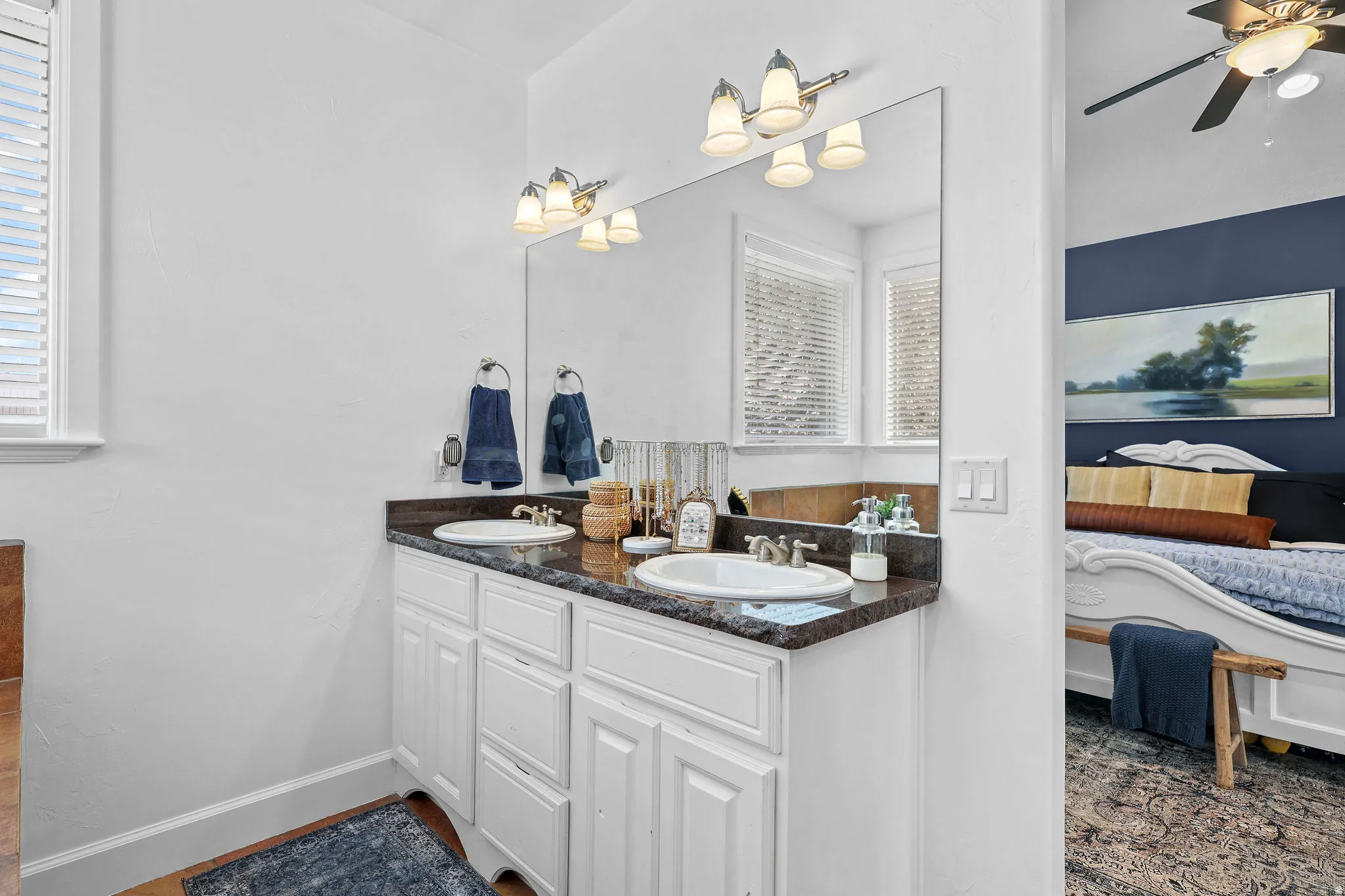 Dual vanity with integrated sinks, dark stone-finish countertop, and white cabinetry