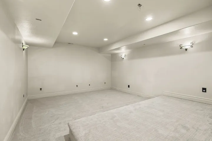 Recessed lighting, wall sconces, plush carpet flooring, and a raised platform
