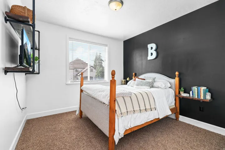White walls with a contrasting accent wall, ceiling-mounted light fixture, window with horizontal blinds, and carpeting