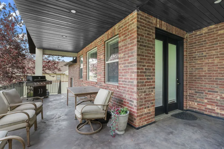 Covered patio with brick exterior, concrete flooring, and recessed lighting