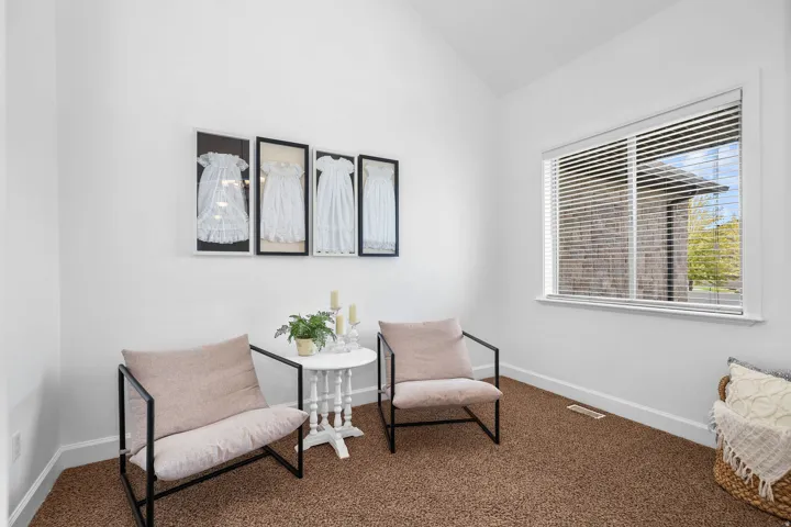 Vaulted ceiling, white walls, large window with blinds, and brown carpet flooring