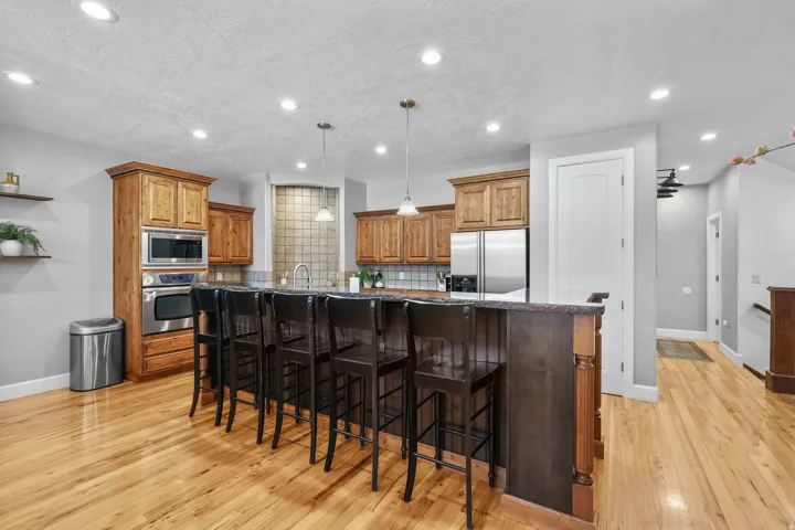 Wood-finish flooring, recessed lighting, wood cabinetry, stainless steel appliances, and a kitchen island with pendant lighting
