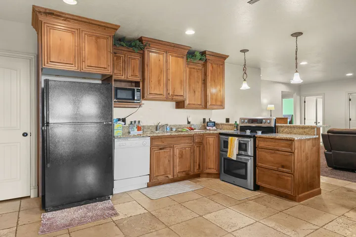 Kitchen featuring wood cabinetry, light-toned stone tile flooring, granite-style countertops, stainless steel oven, and a built-in microwave
