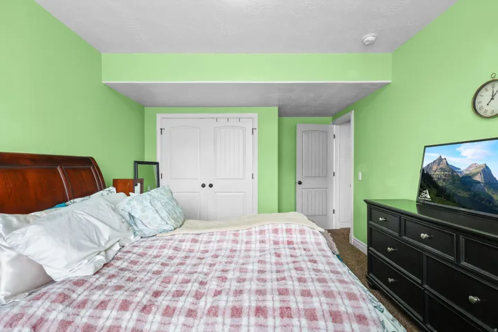 Recessed ceiling area, wood-finish headboard, white paneled double closet doors with dark hardware, white paneled door with dark hardware, and carpet flooring