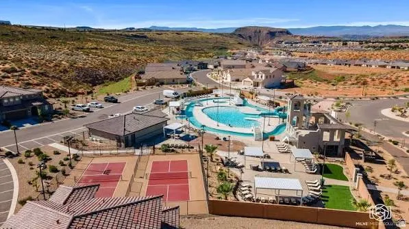 Community swimming pool with water slides, adjacent pool house, multiple tennis courts, and surrounding open space