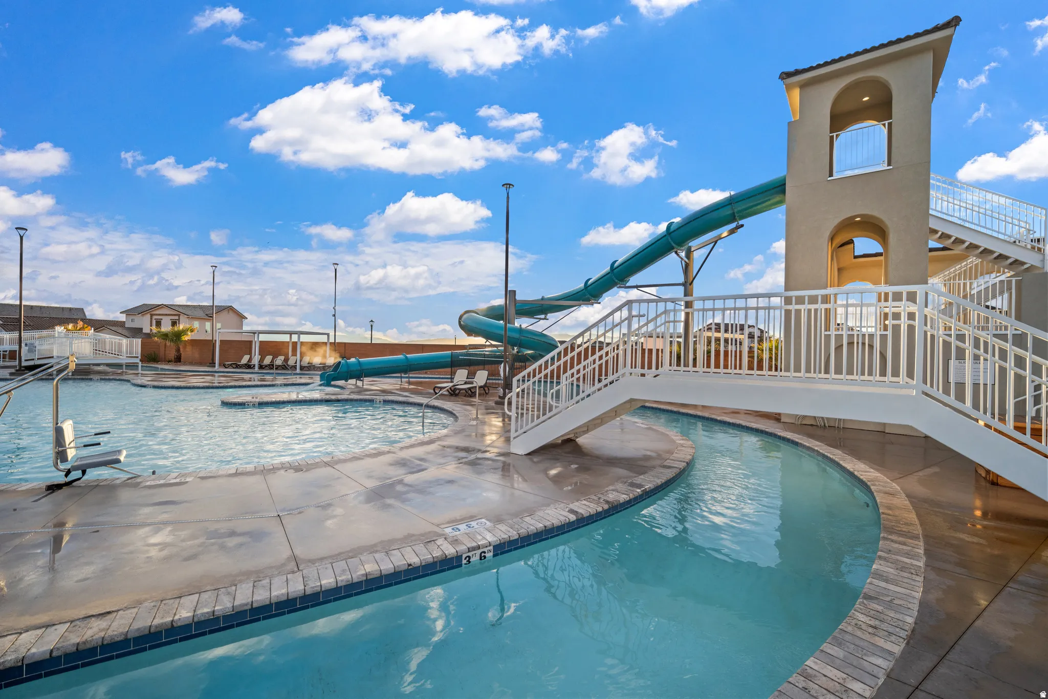 Resort-style pool with a waterslide, a lazy river, and a multi-level tower structure featuring a staircase and arched openings