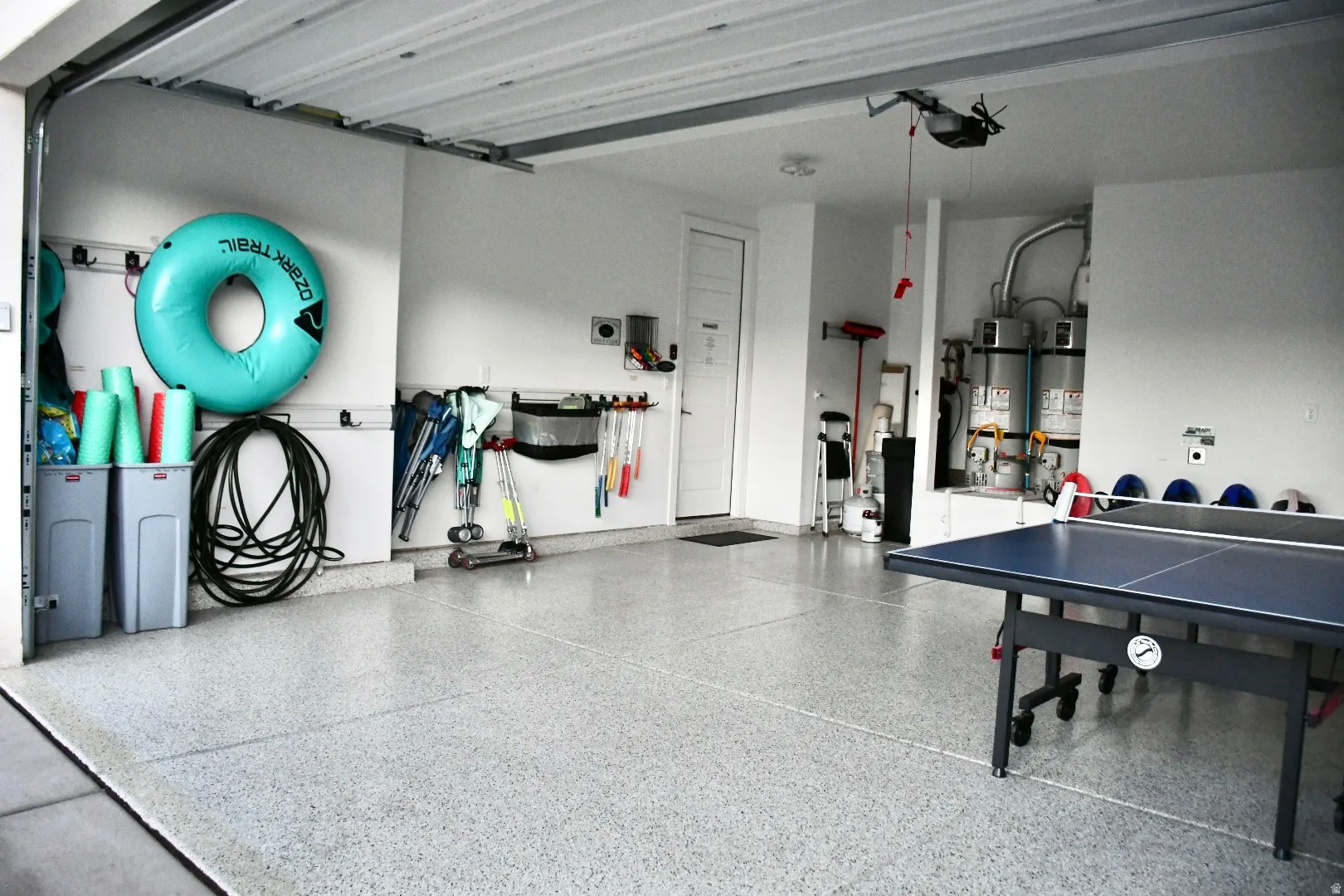 Attached garage with a roll-up door, neutral wall paint, and a durable epoxy floor finish