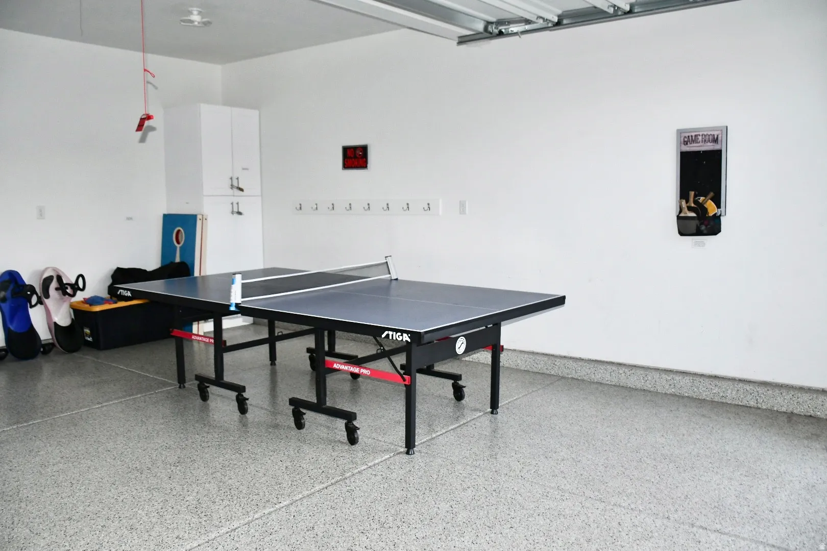 Garage with white walls, built-in white cabinetry, coat hooks, and speckled epoxy flooring