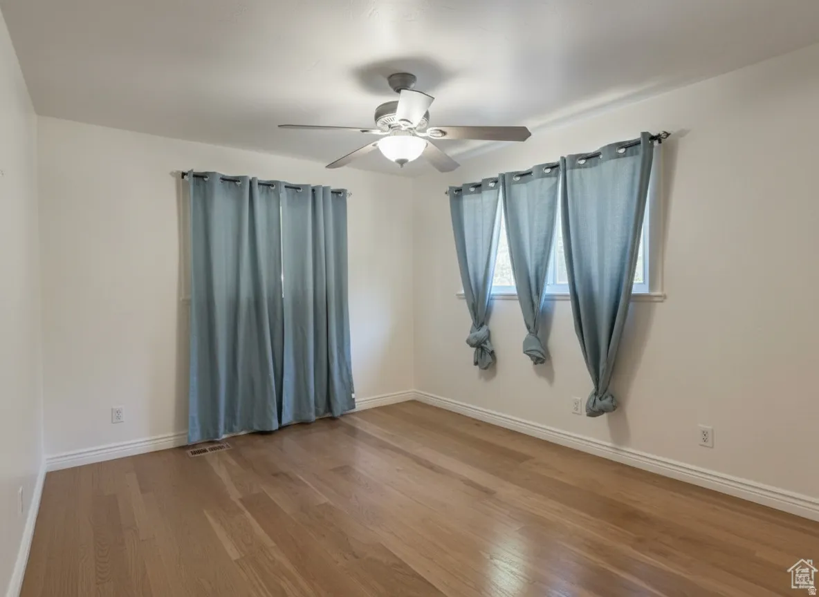 Wood-finish flooring, ceiling fan, and multiple windows with natural light