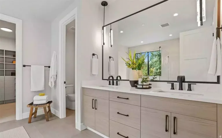 Bathroom featuring a dual vanity with light-toned cabinetry and black hardware