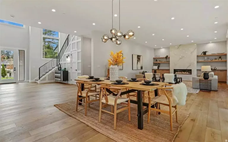 Open-concept living space with wood-finish flooring, a contemporary fireplace with a stone surround, and integrated shelving