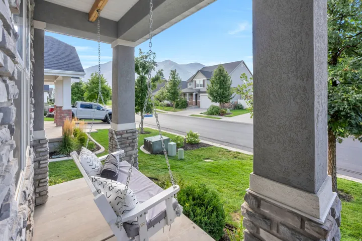 Front porch featuring stone facade, textured pillars, and a porch swing