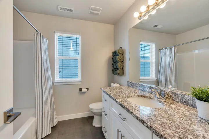 Bathroom featuring a white vanity with granite-style countertop, undermount sink, and a large mirror with overhead lighting