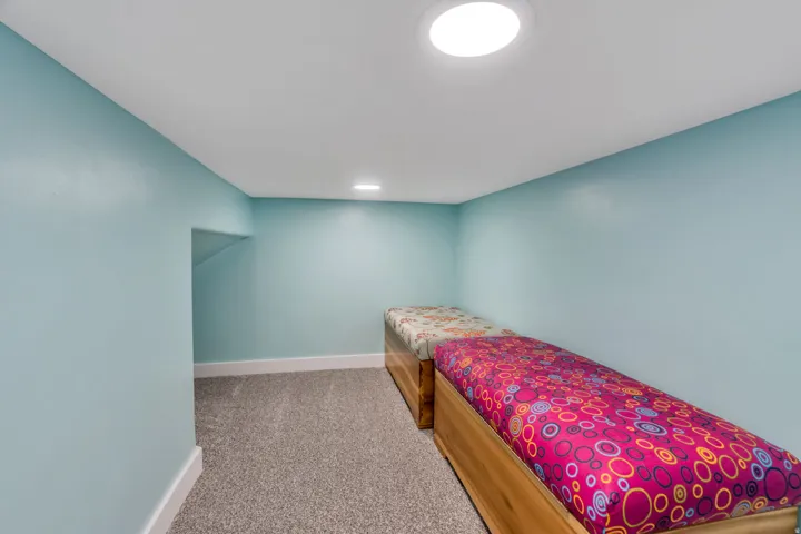 Recessed lighting, light blue wall paint, gray carpeting, and white trim