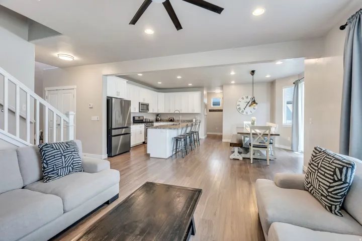 Spacious living area with wood-finish flooring, white kitchen cabinetry, stainless steel appliances, and an eat-in dining area