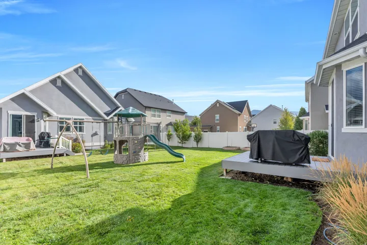 Expansive grassy yard with two distinct outdoor decks and a white privacy fence