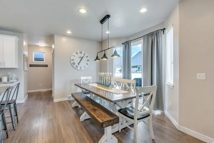 Wood-finish flooring throughout, white upper cabinetry, recessed lighting, and a multi-bulb linear pendant light fixture