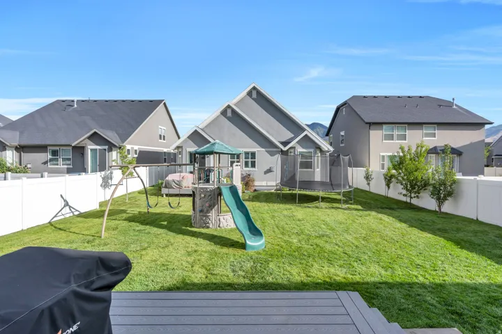 Expansive backyard featuring a manicured lawn, full privacy fencing, and a multi-level deck for outdoor living