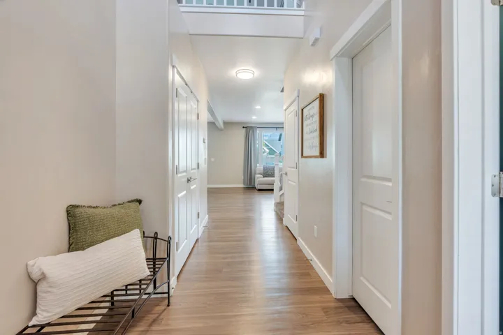 Hallway featuring wood-finish flooring, white paneled doors, and recessed lighting