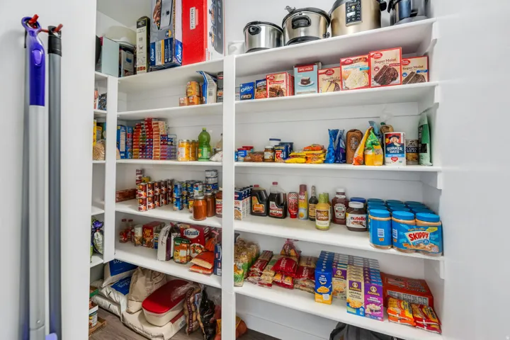 Built-in pantry shelving featuring white finishes and wood-finish flooring