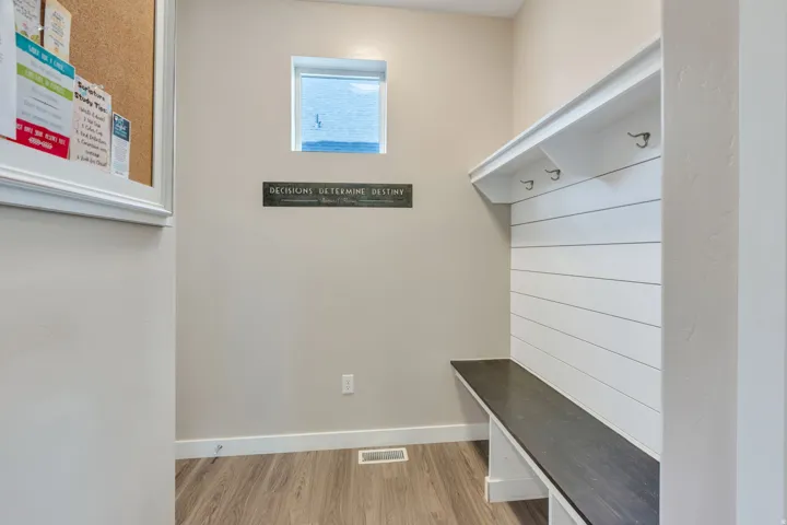 Built-in bench with a dark wood-finish surface, white shiplap-style backing, and integrated coat hooks
