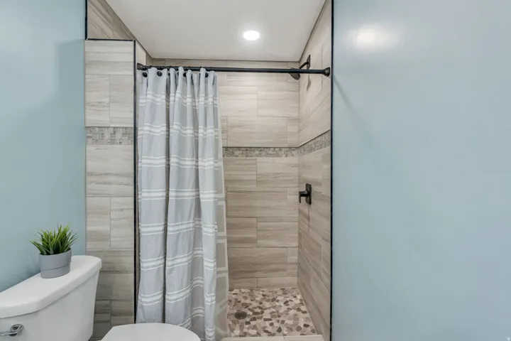 Walk-in shower with vertical tile surround and decorative accent band