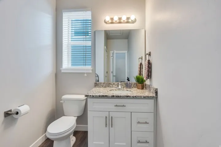 White vanity with brushed nickel hardware, granite-style countertop, and integrated sink