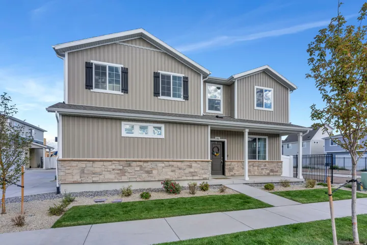 Two-story residence featuring vertical siding, stone facade accents, a covered front porch, and black exterior shutters
