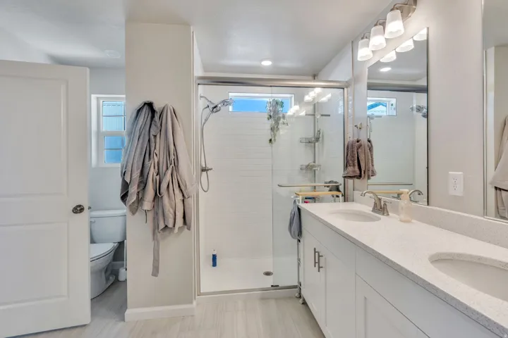 Primary bathroom featuring Dual vanity with composite countertops, white shaker cabinetry, and brushed nickel hardware
