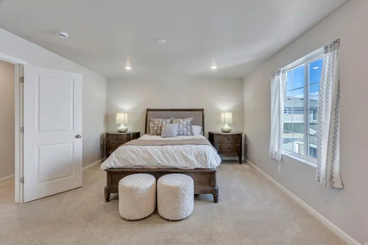 Primary Bedroom located on the Second level. Recessed lighting, light gray wall finishes, light carpeting, and a window with white trim