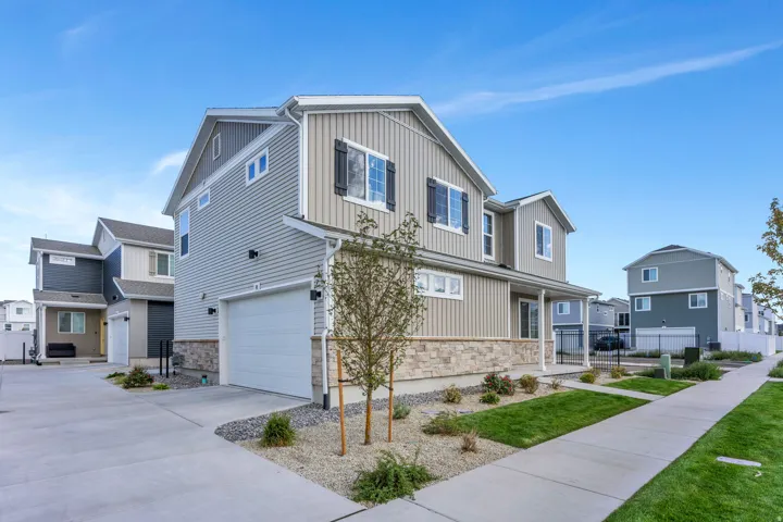 Two-story exterior with light gray siding and stone veneer accents. Snow Removal on Driveway covered by the HOA.
