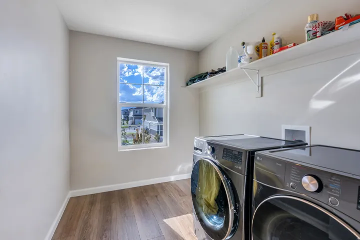 Dedicated laundry space featuring wood-finish flooring, a window, and an integrated shelf