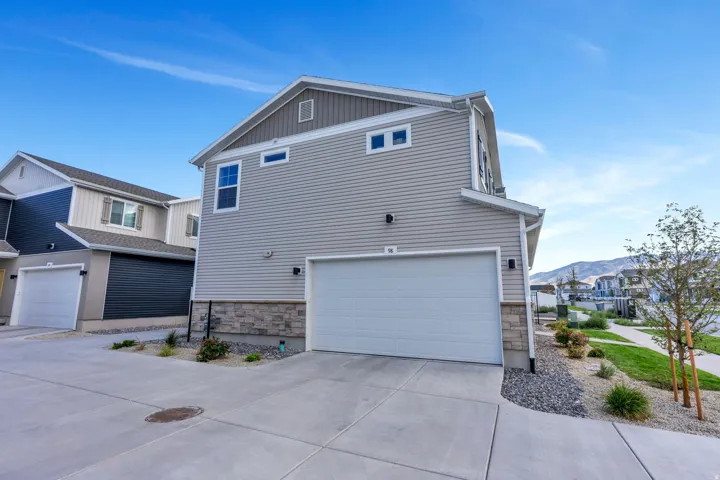 Attached two-car garage with a concrete driveway, complemented by a stone accent façade. Snow Removal on Driveway covered by the HOA.