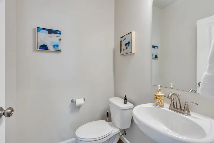 Half Bath on Main Level. Pedestal sink with a brushed nickel faucet and a wall-mounted mirror
